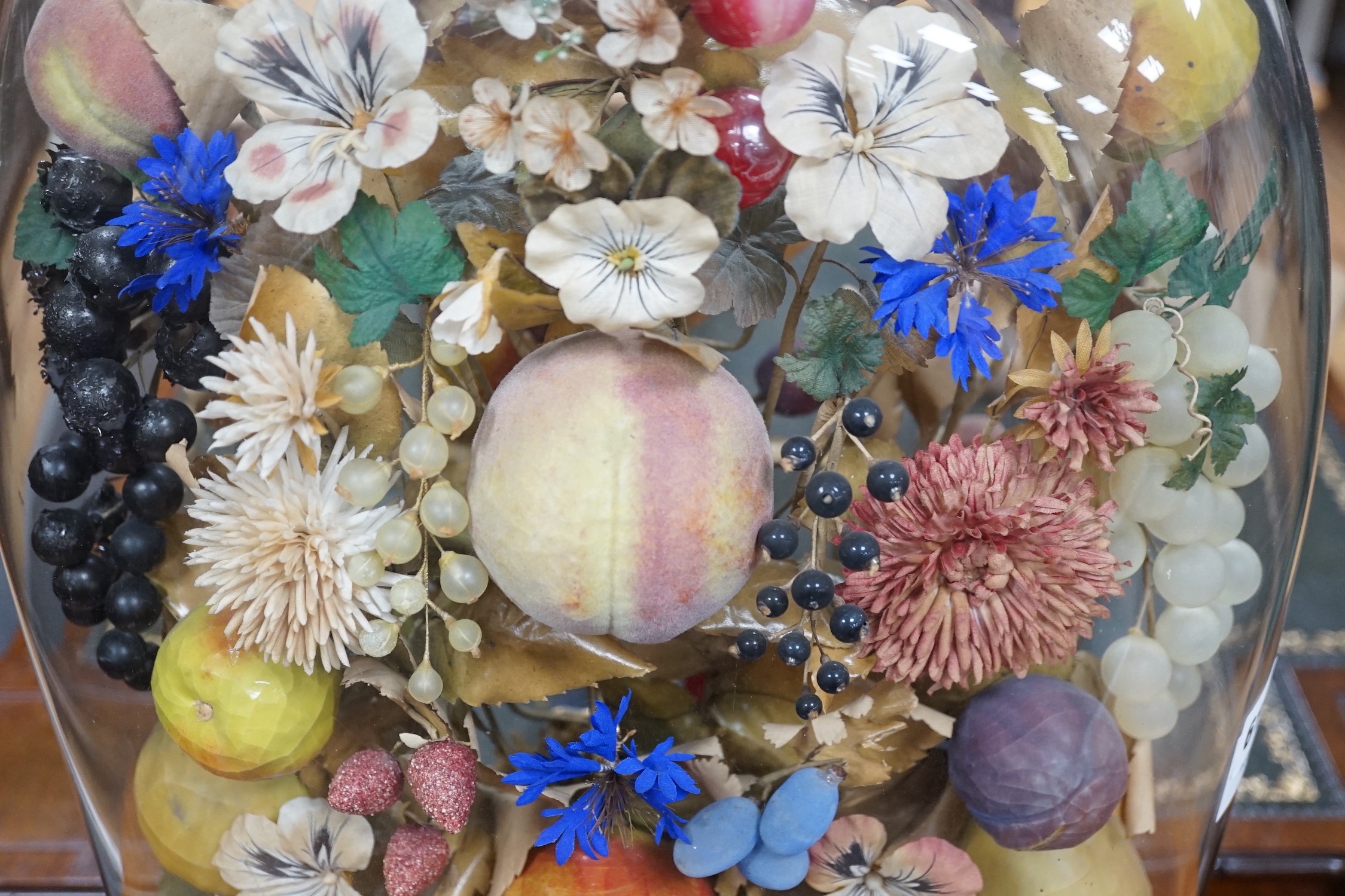 A Victorian painted mache fruit arrangement under a glass dome, 58cms high